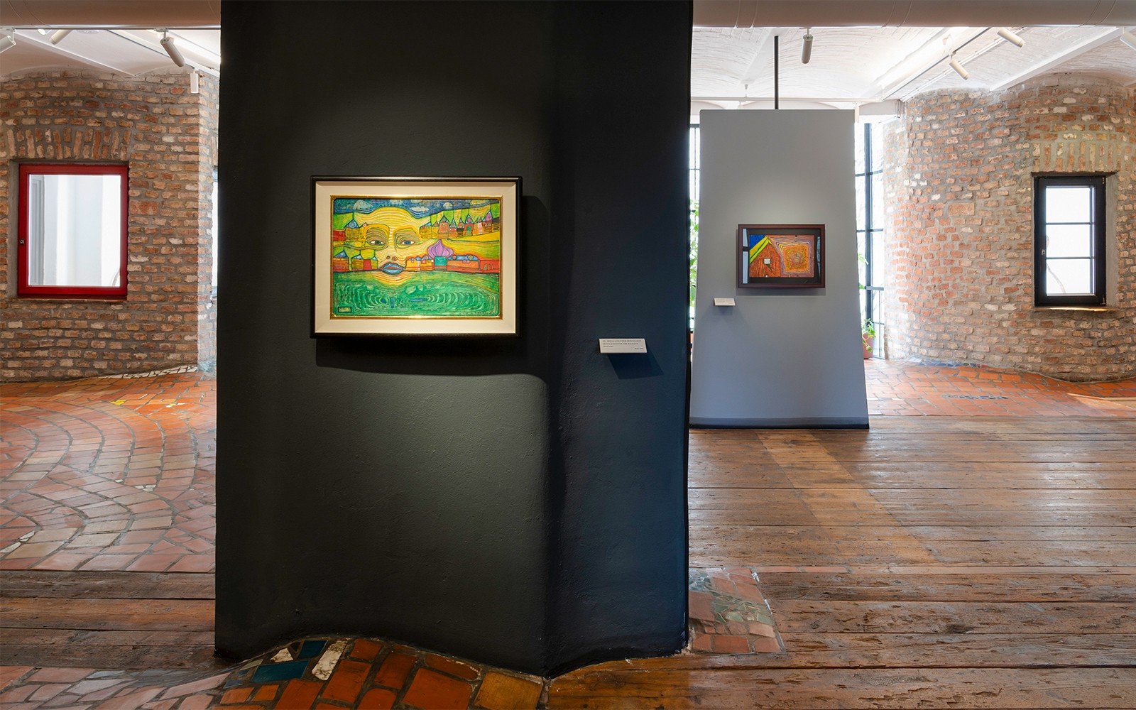 Pameran di KUNST HAUS WIEN menampilkan lukisan-lukisan warna-warni Hundertwasser di dinding bata.