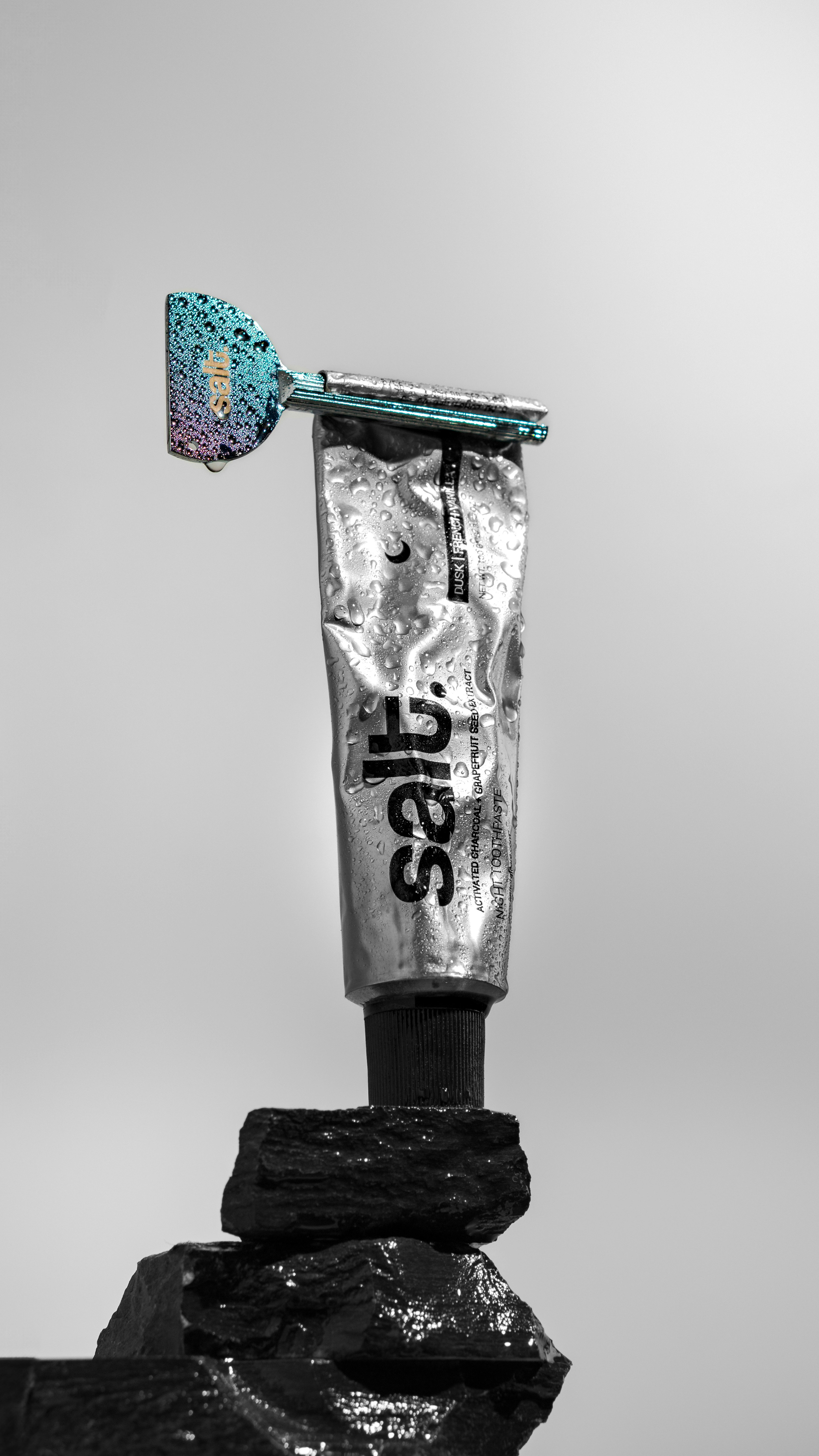 Shaving cream tube with a razor balanced on rocks.