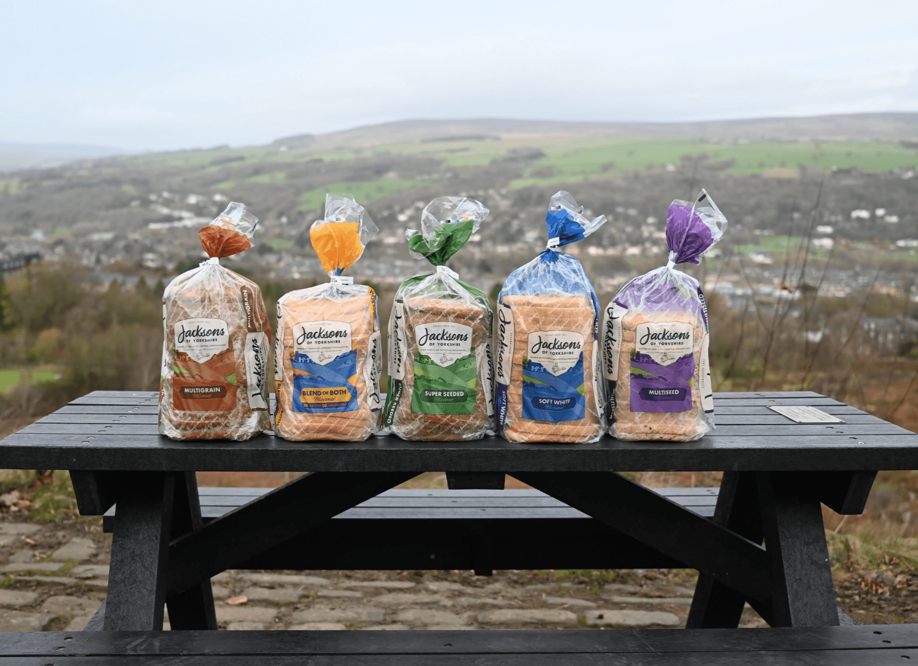 Five loaves of bread on a picnic bench overlooking the Yorkshire Dales