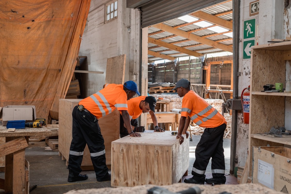Team of workers assembling heavy-duty wooden packaging for a turnkey project.