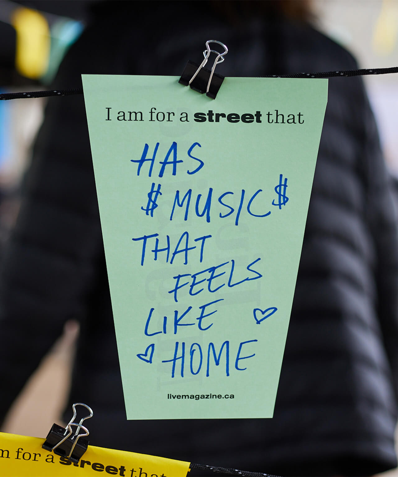 Closeup of a hand-written note reading "I am for a street that has music that feels like home".