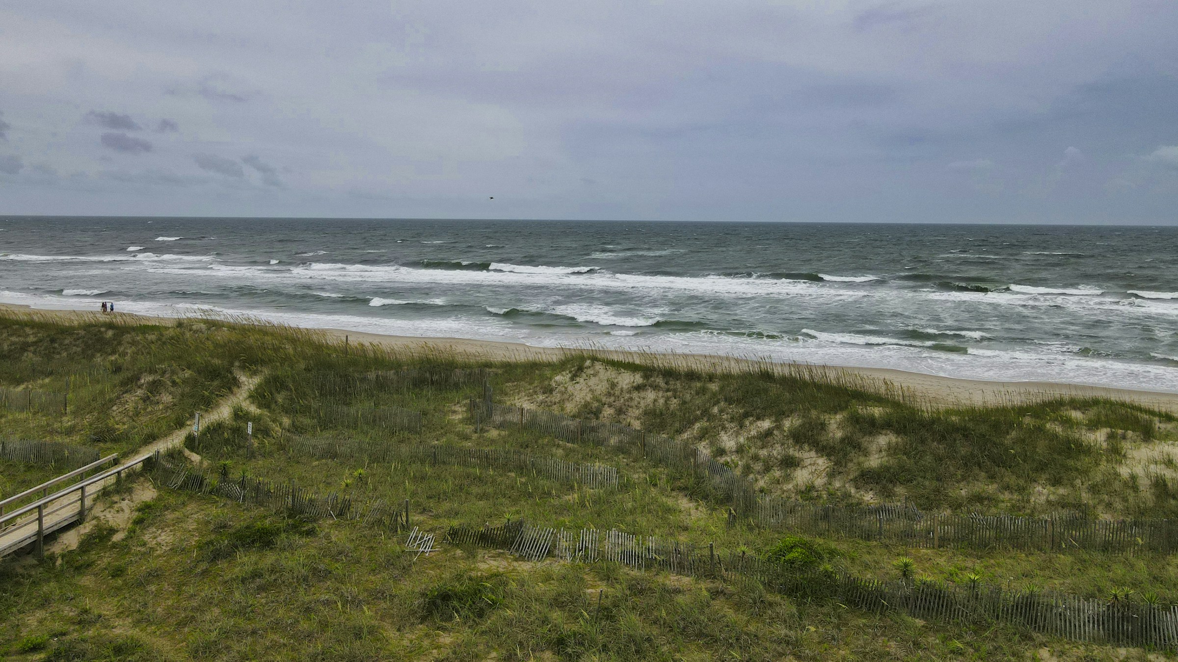 OBX wide sandy beach with a wooden walkway over dunes leading to the Atlantic Ocean on Hatteras Island