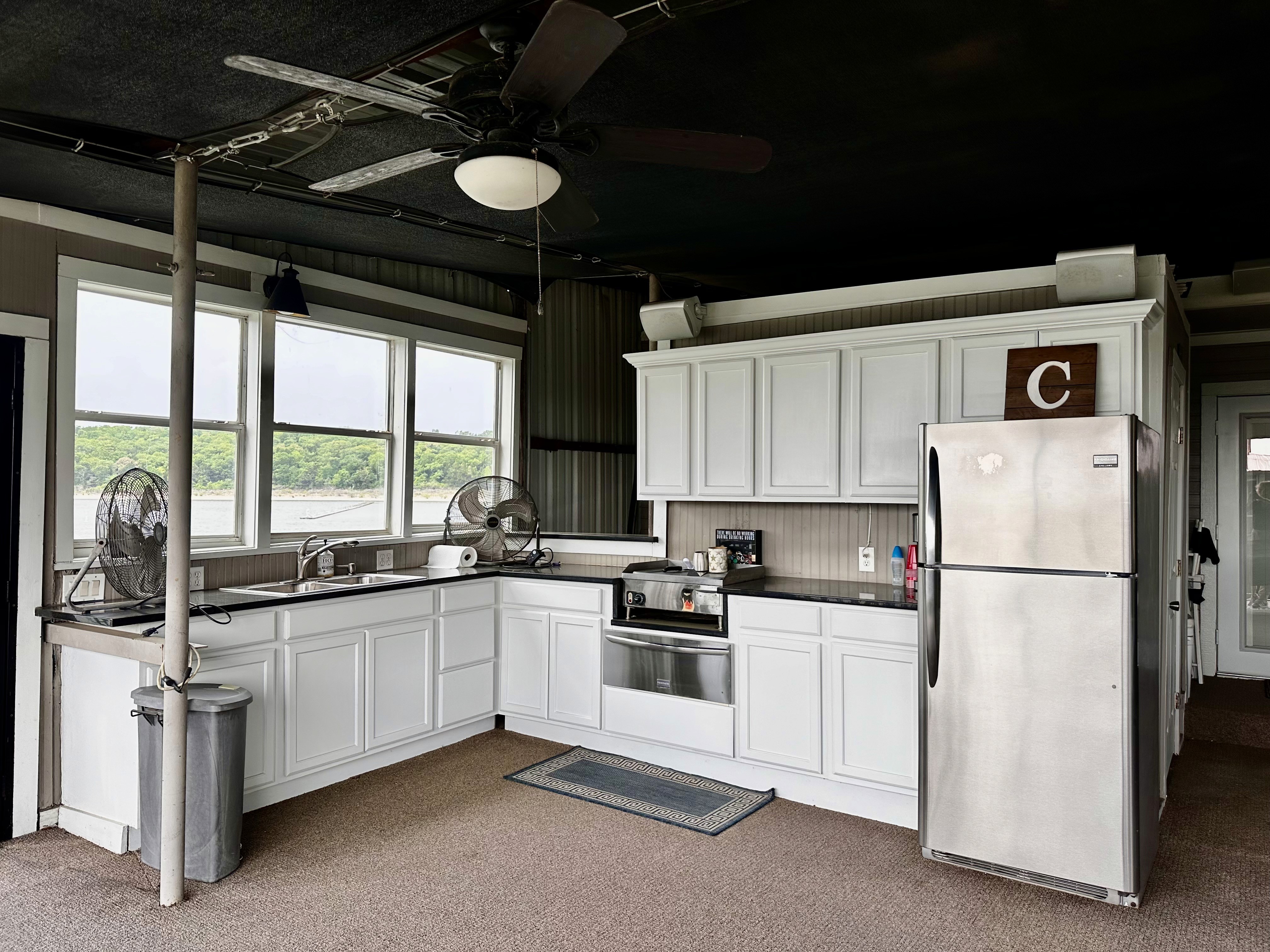Kitchen with white cabinets, stainless steel appliances, and a ceiling fan. Includes a sink, and windows with a view.