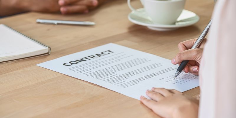 A woman signing a contract to secure a supplier