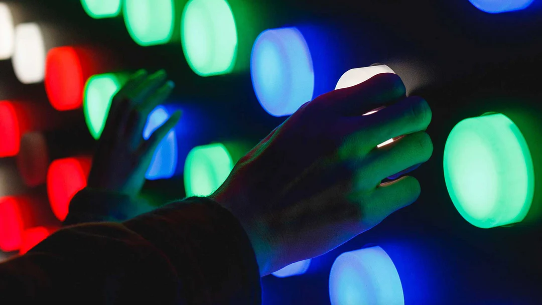 hands touching glowing green, blue, red and white buttons