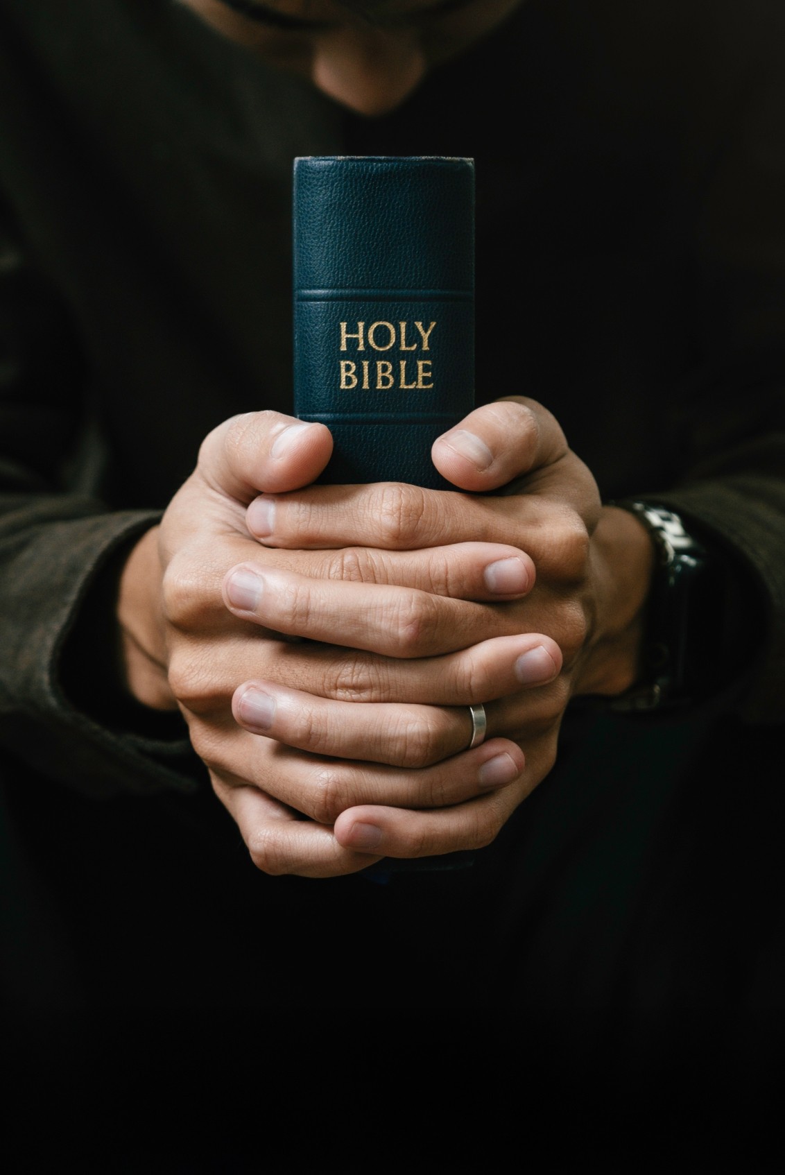 man kneeling down praying holding bible in hands