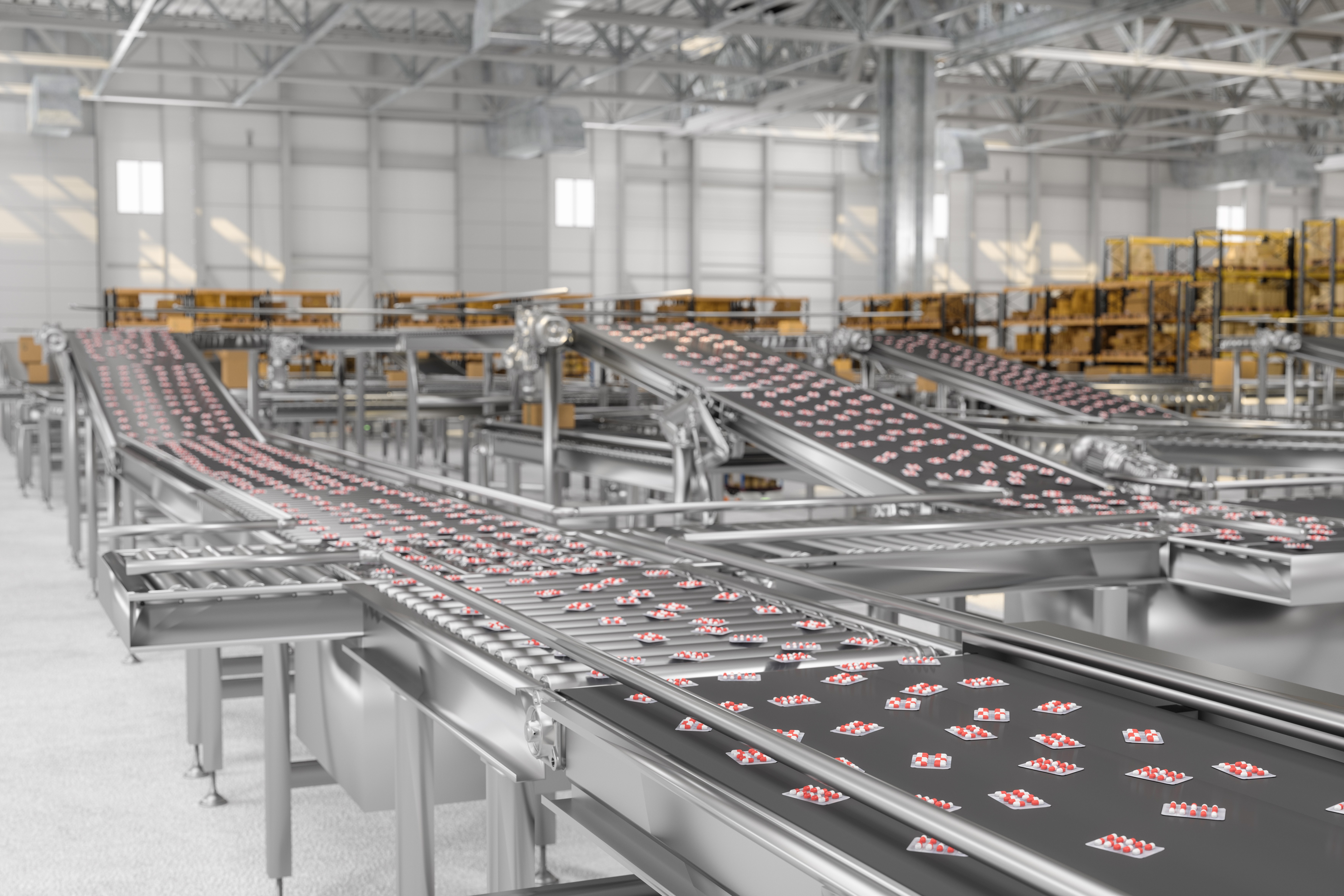 The image shows a modern, industrial chocolate factory production line with multiple conveyor belts carrying individually wrapped chocolates in a spacious, well-lit facility.