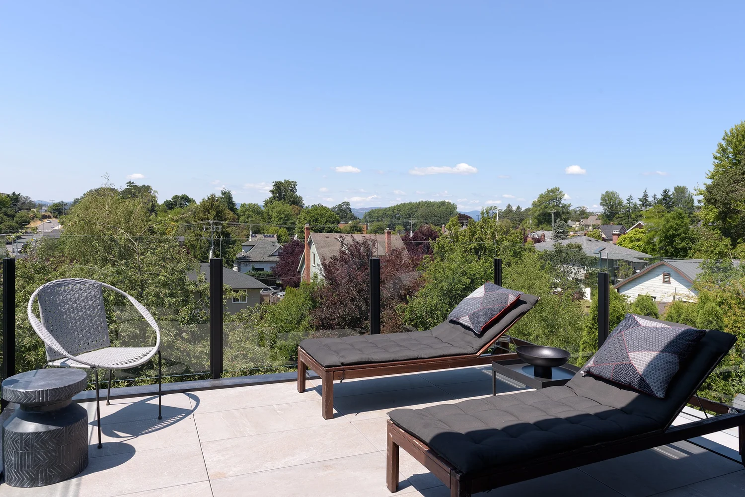 Modern two-story home with large glass windows, warmly lit interiors, and a balcony. Surrounded by trees and a manicured lawn at dusk. Cozy ambiance.