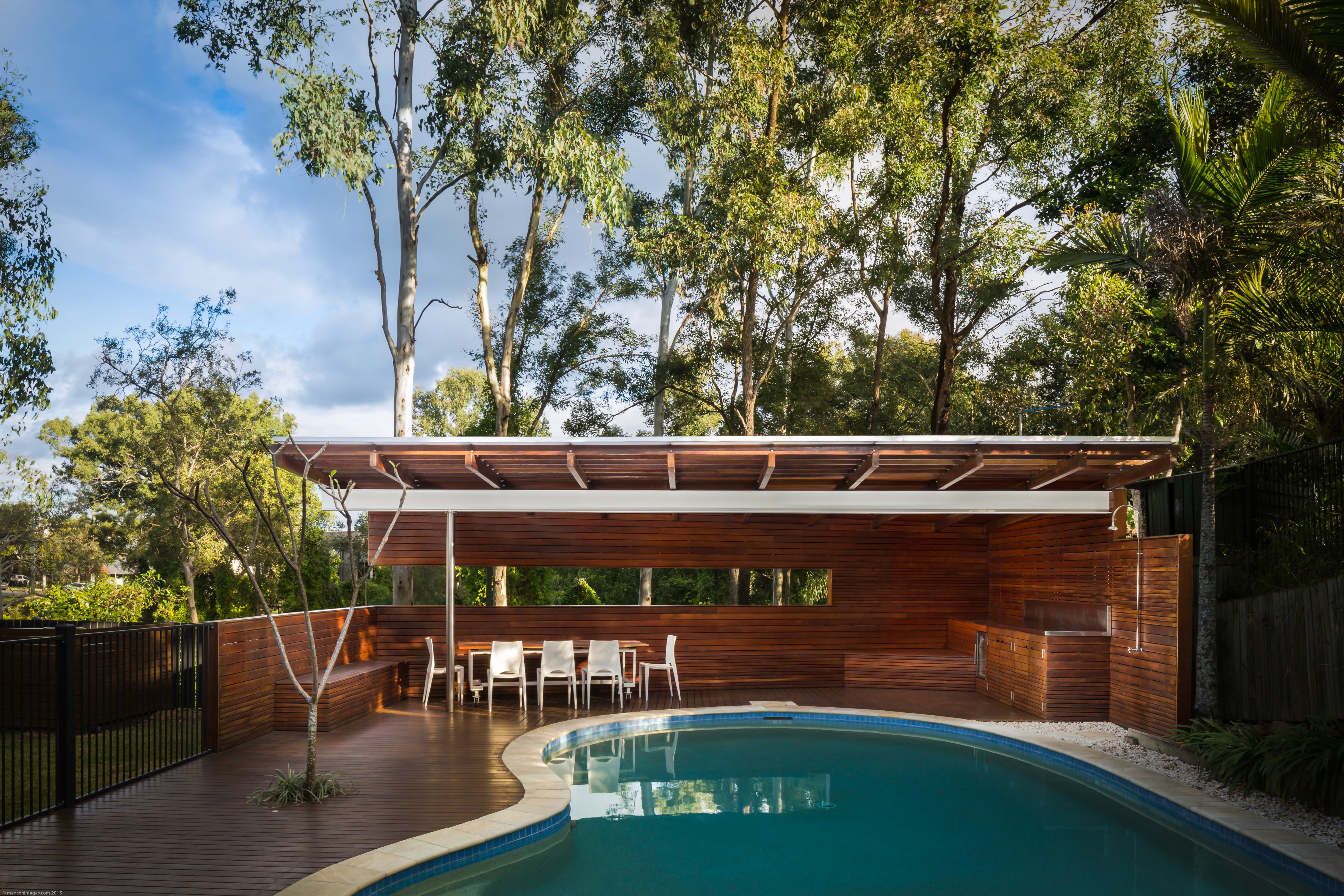 Front-on view of Wattle Pavilion, showing the timber structure, shallow pitched roof, and its close relationship to the pool and surrounding landscape.