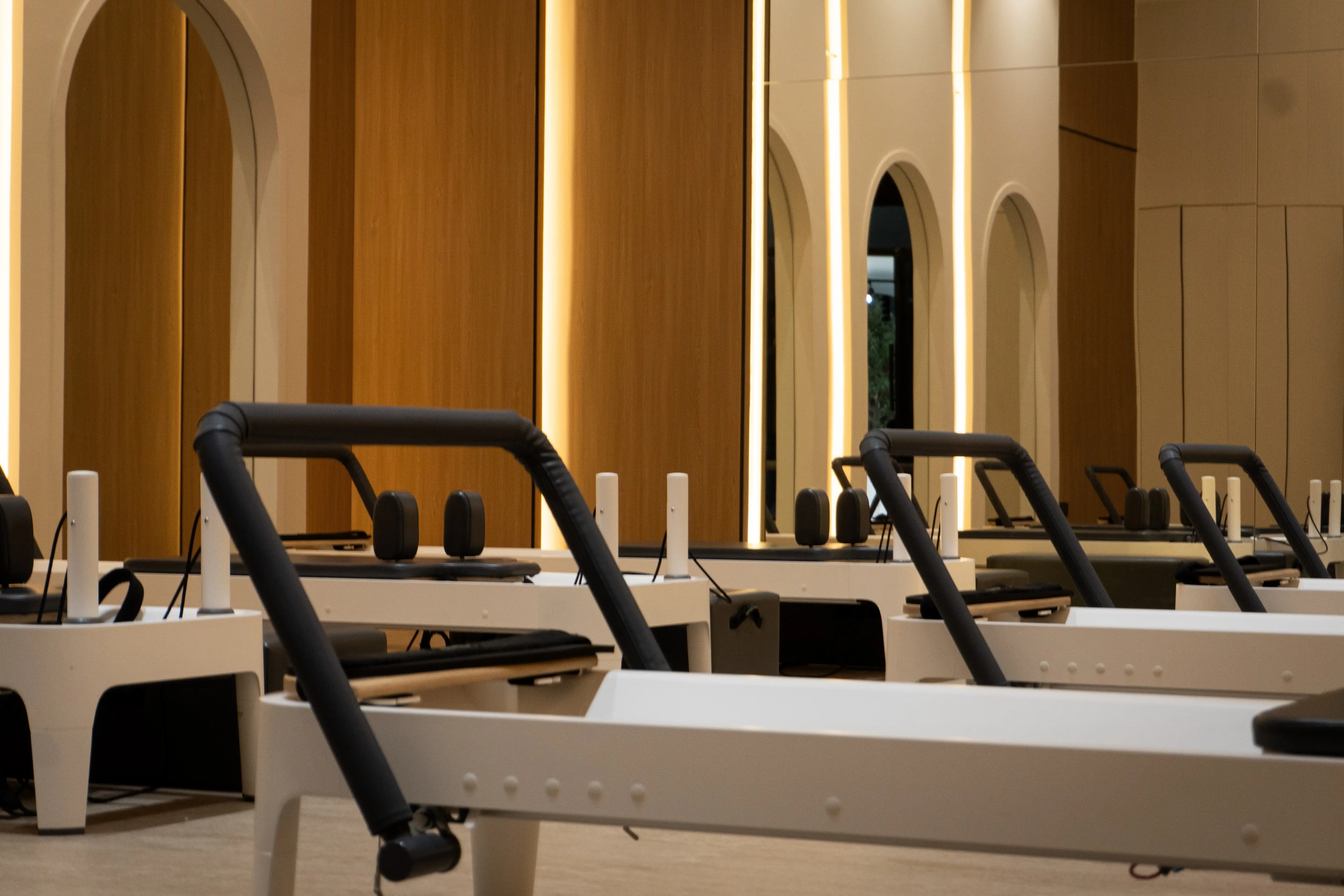 Reformer Pilates machines in a warm-toned room designed for women’s Pilates.