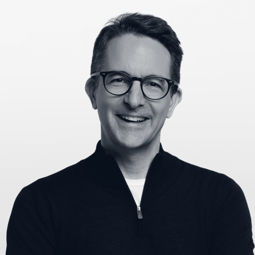 Portrait of a man with short dark hair and a trimmed beard, dressed in a dark shirt, on a simple background.