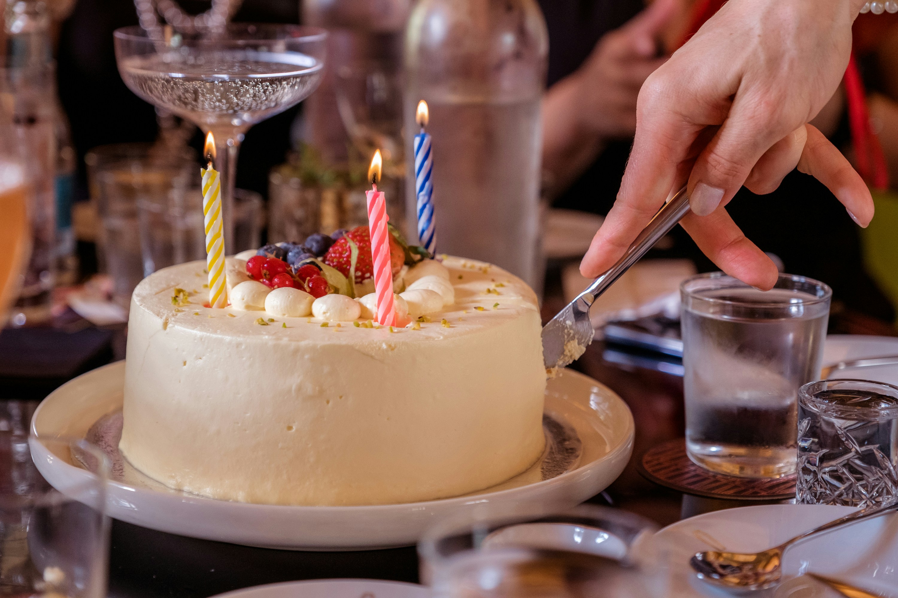 A person cutting a cake with candles on it