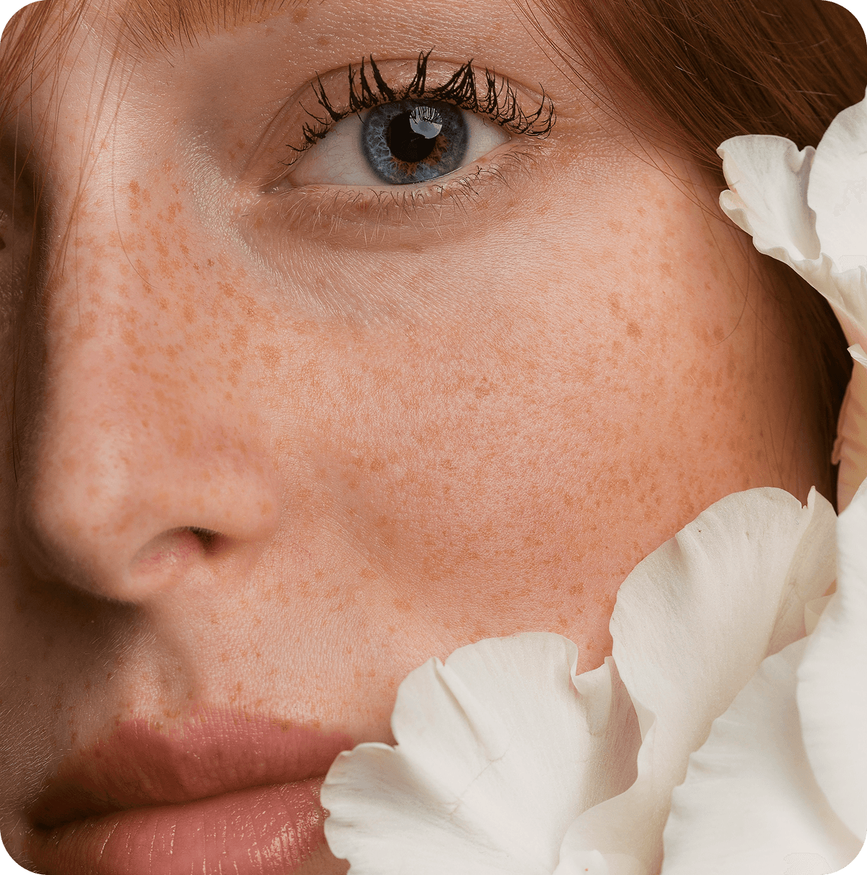 Portrait of a woman with short brown hair, eyes closed, gently touching her face with both hands against a beige background