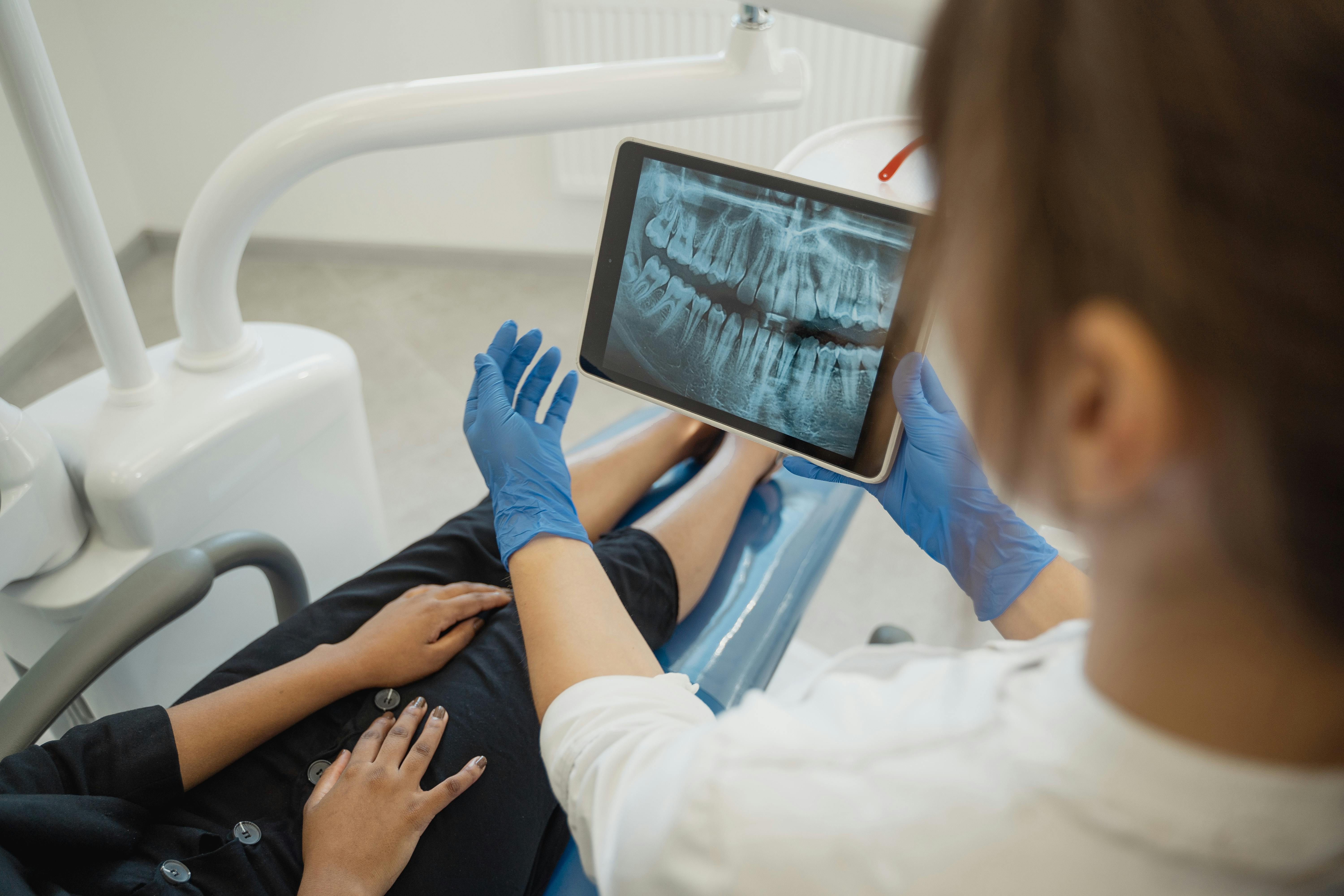 dental hygienist using ipad to show xrays to patient