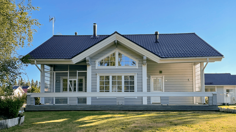 Ulkomaalattu hirsitalo Seinäjoella, vaaleansininen julkisivu, musta peltikatto ja valkoiset ikkunalistat, siisti vihreä piha-alue edessä.