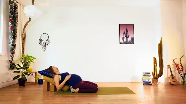 Pregnant woman in a supported floor yoga pose – prenatal yoga class to optimise pelvic positioning and stability for a smoother birth