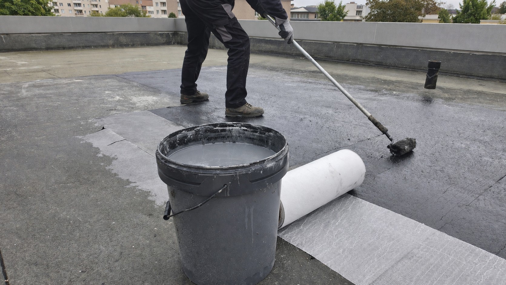 Photo réaliste d’une application de résine d’étanchéité sur une toiture terrasse, avec surface de toit en rénovation, texture du revêtement visible et rendu terrain pour illustrer le choix d’une résine d’étanchéité toiture