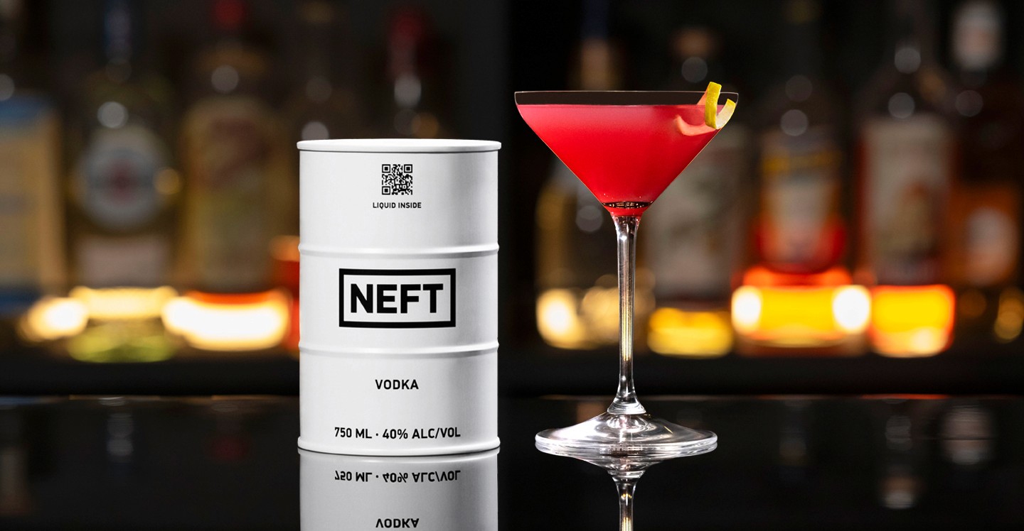 A NEFT Barrel and a glass of Pomegranate Martini on a bar counter.