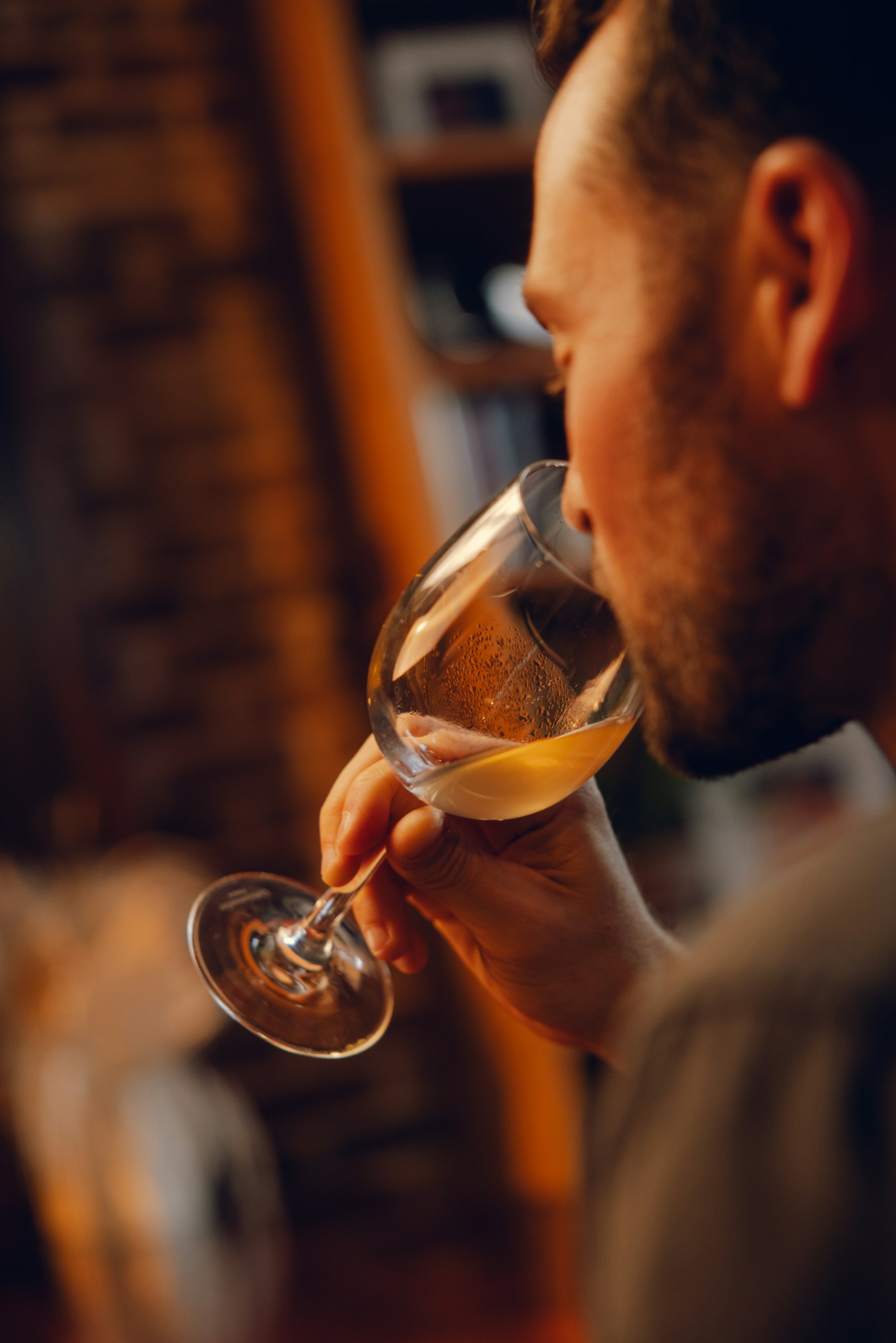 A young woman with long hair smiles while standing against a green backdrop, wearing a casual dark sweater.