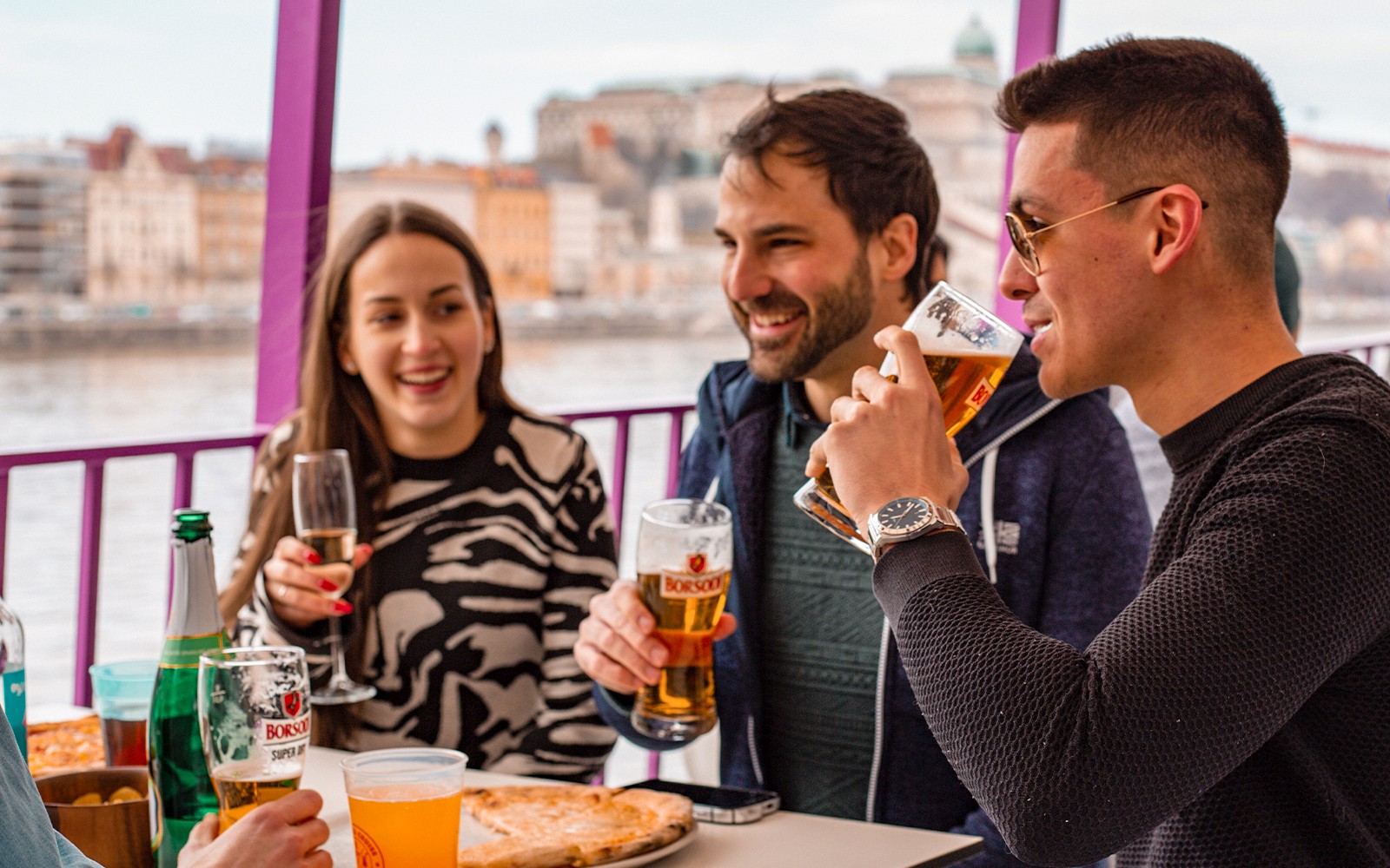 Danube River cruise in Budapest with tourists enjoying pizza and unlimited drinks on a party boat.
