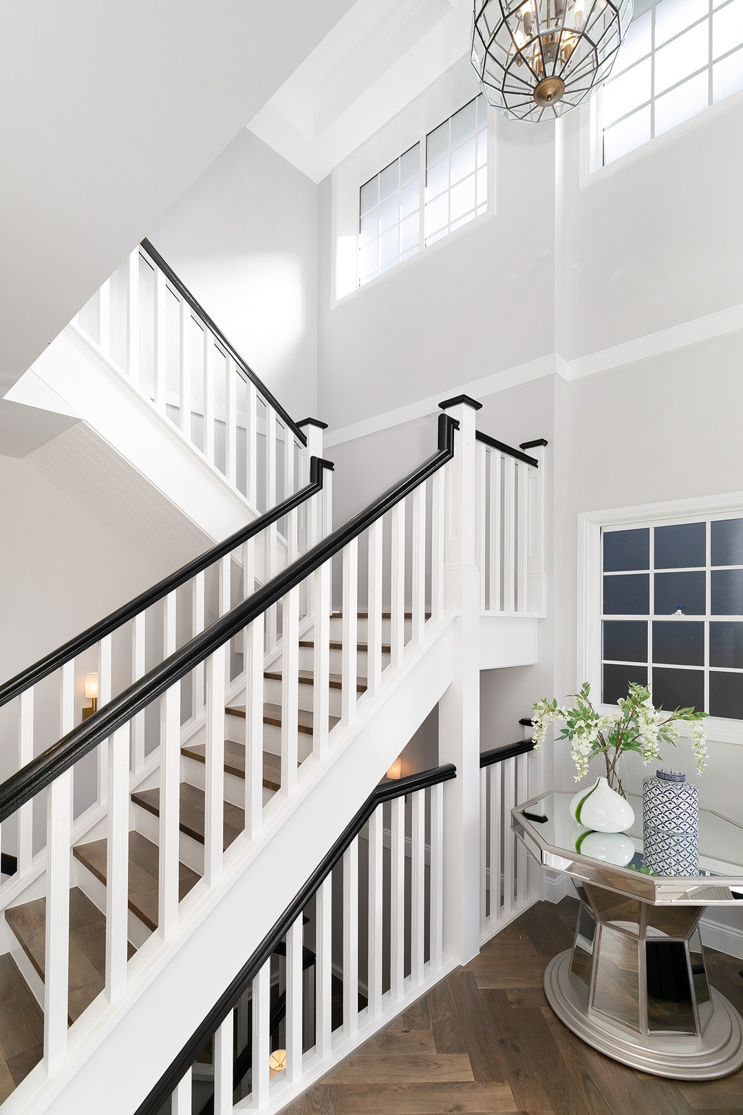 A staircase at the entryin this Hamptons style home with a void above the staircase