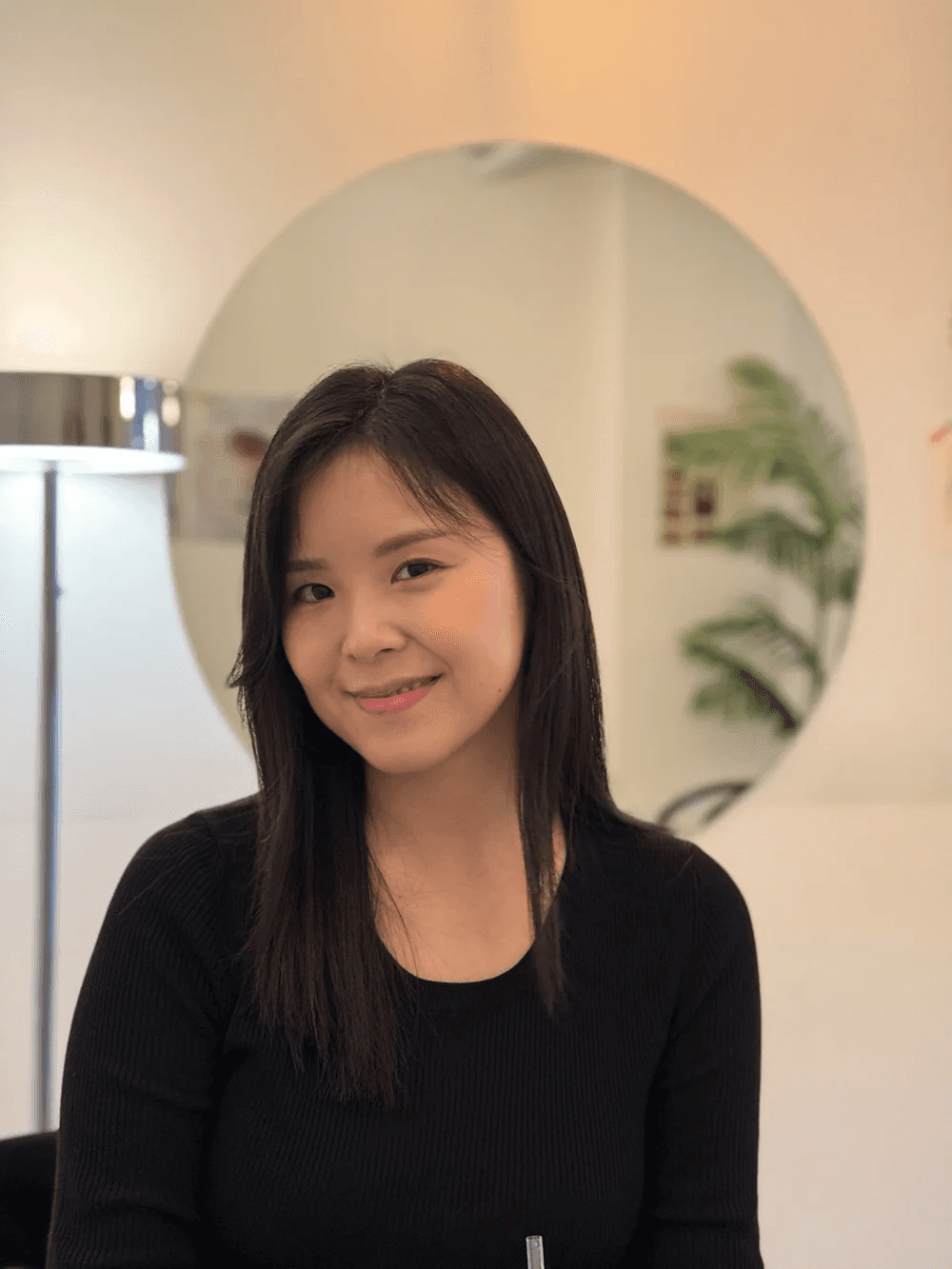 Person wearing a blue puffer jacket and red backpack standing in front of a light blue building on a city street.