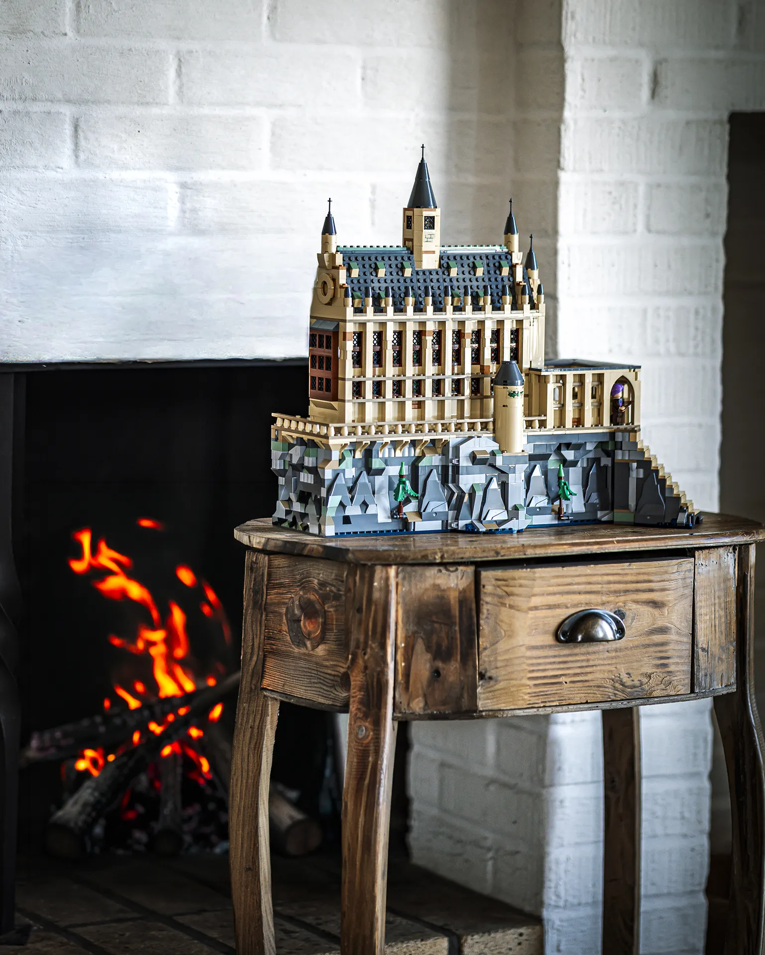 LEGO Harry Potter-modell av Galtvort slott utstilt på et trebord ved siden av en peis