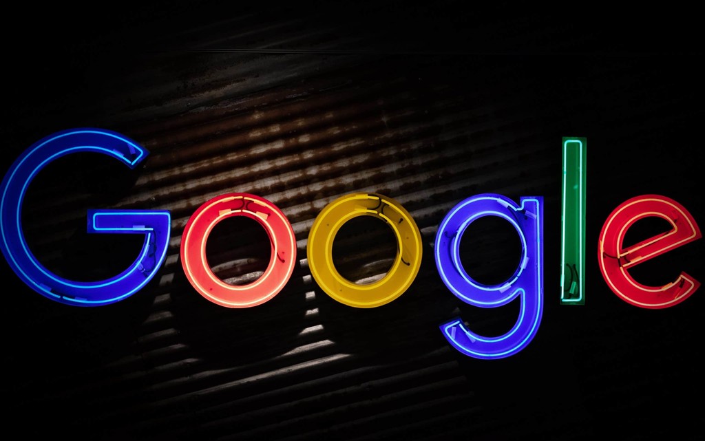 Colorful Google logo in neon lights against dark background.