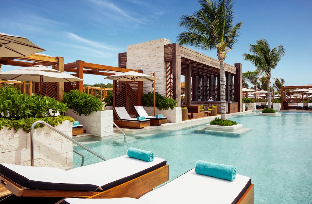 Couple standing on a balcony with binoculars in hand looking out over the ocean