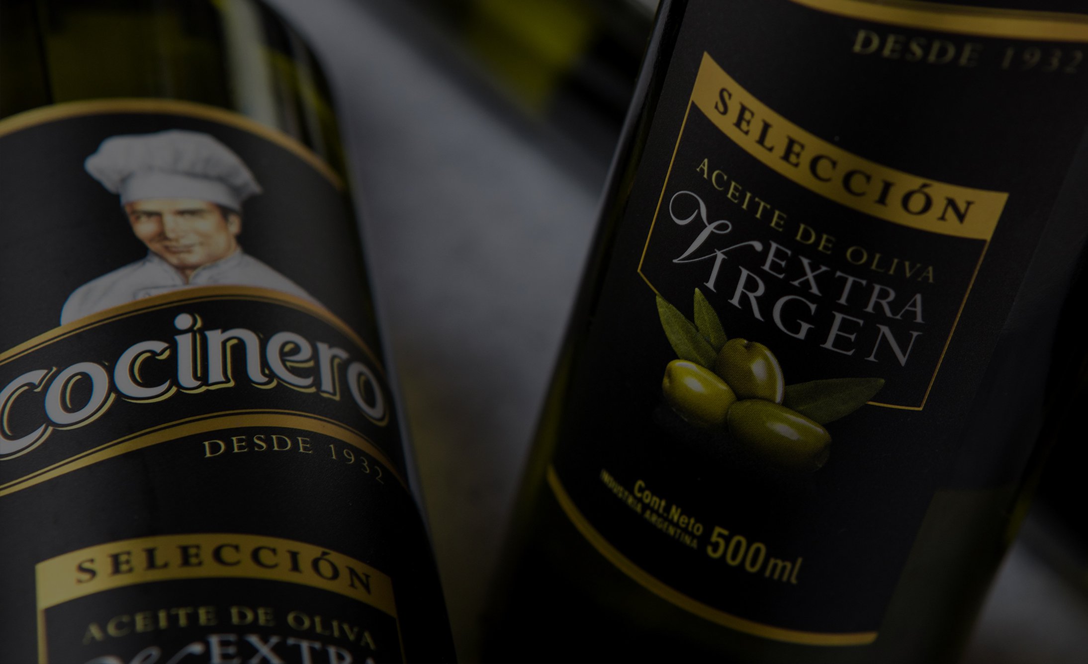 Two bottles of olive oil are shown, featuring labels with a chef image and green olives. The text reads "Selección Aceite de Oliva Extra Virgen, 500ml.