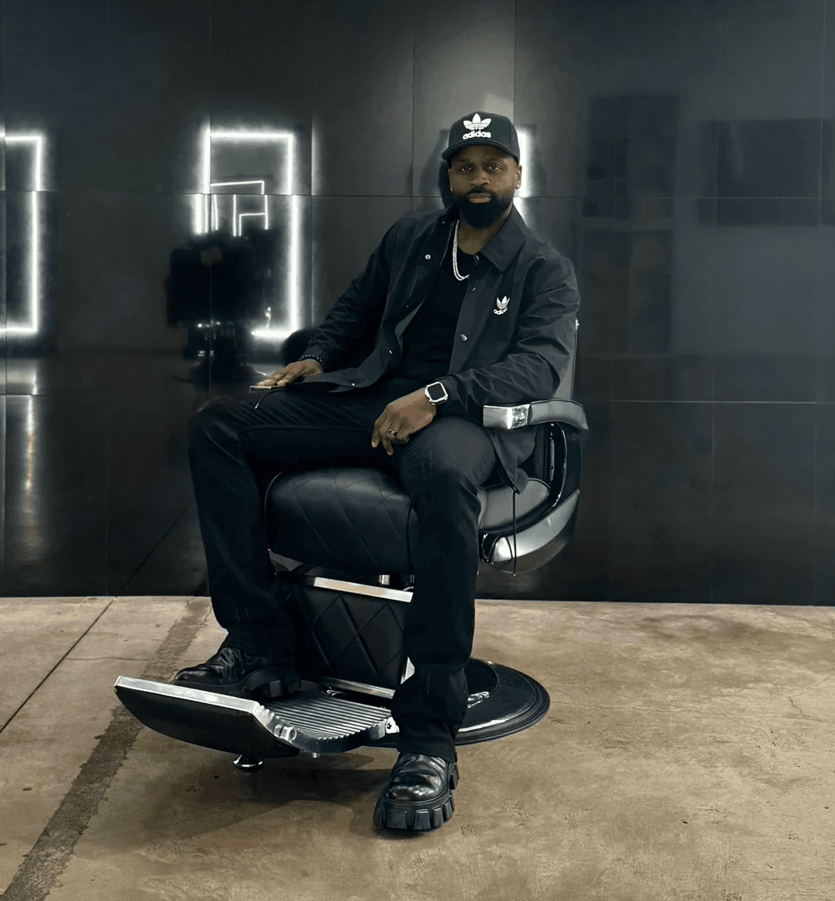 Courtney Palmore, also known as Barber.CLP, sitting confidently in a barber chair, showcasing expertise in luxury barbering and upscale grooming services.