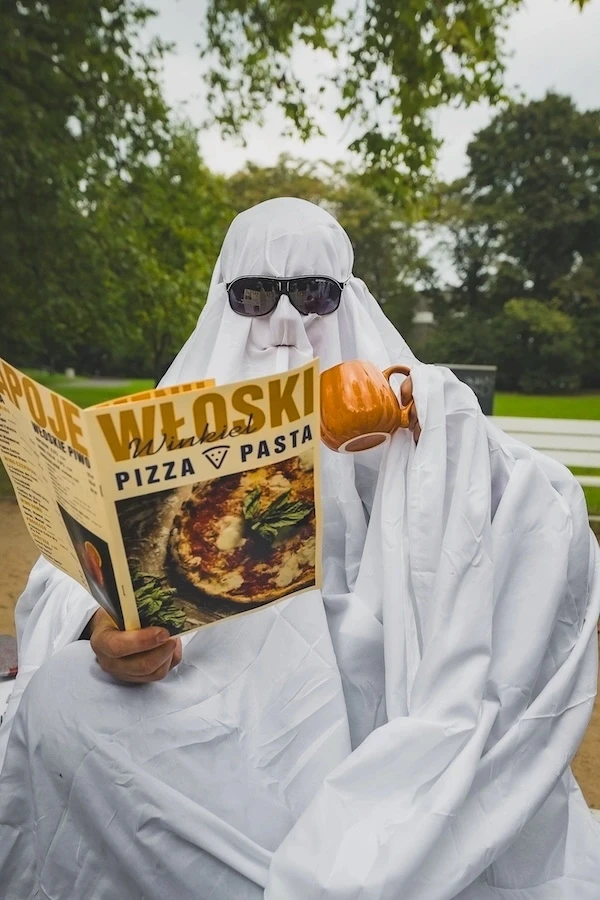 Człowiek przebrany za ducha trzyma menu wloski winkiel