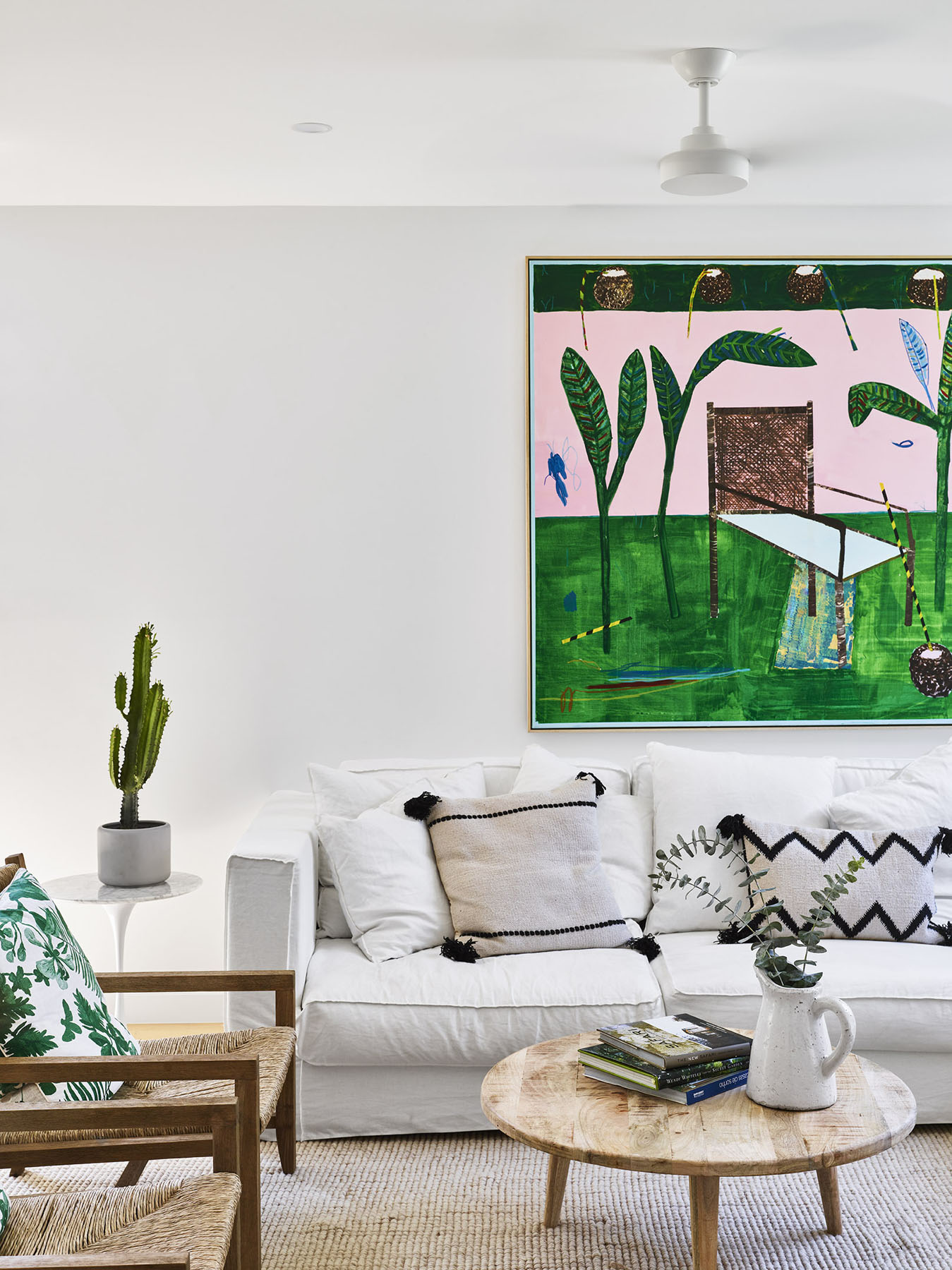Bright living room with white sofa, timber furniture, and large artwork.