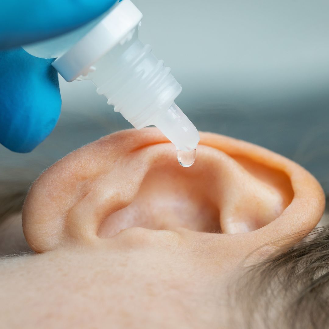 a professional putting ear drops in a small ear