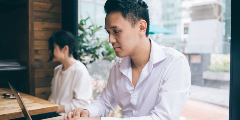 A Malaysian business owner typing on his laptop