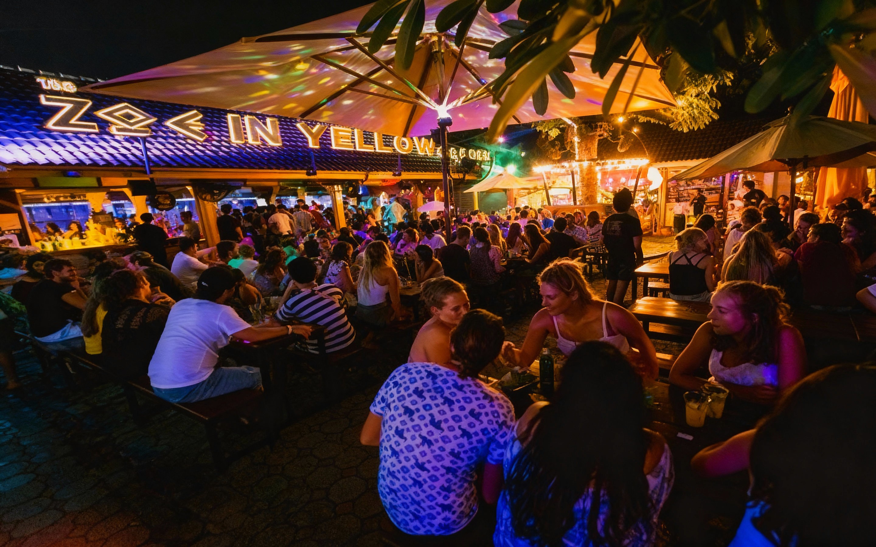 Crowded outdoor bar scene at Zoe in Yellow, Chiang Mai’s most popular nightlife spot, with colorful lights, music, and people socializing under umbrellas in a lively courtyard setting.