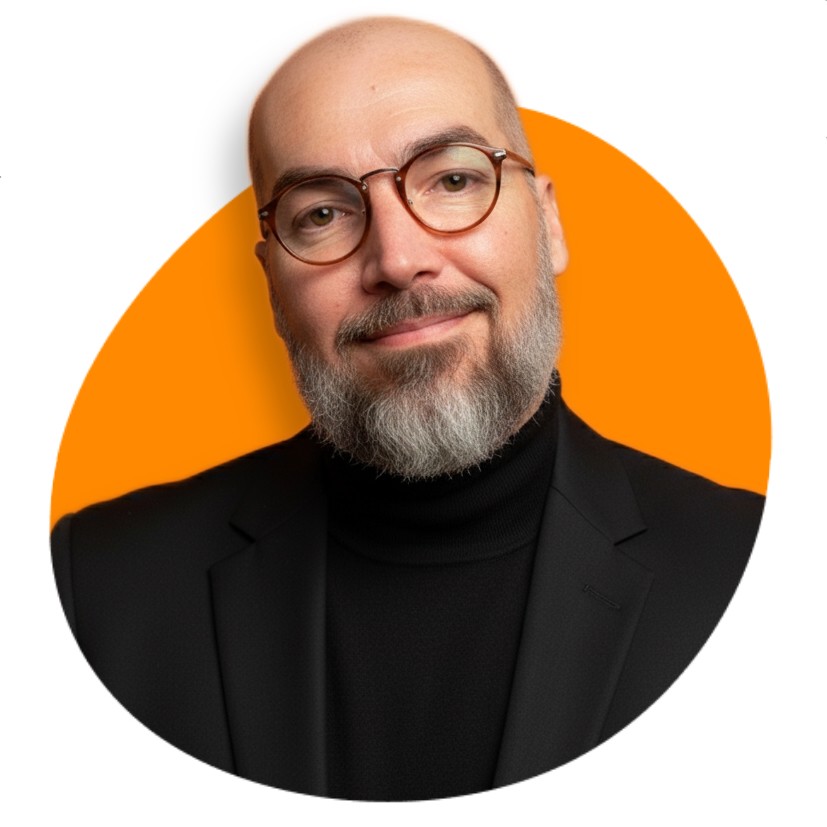 Homem branco, careca, de barba grisalha, usando óculos redondo e blusa preta em um fundo alaranjado. 