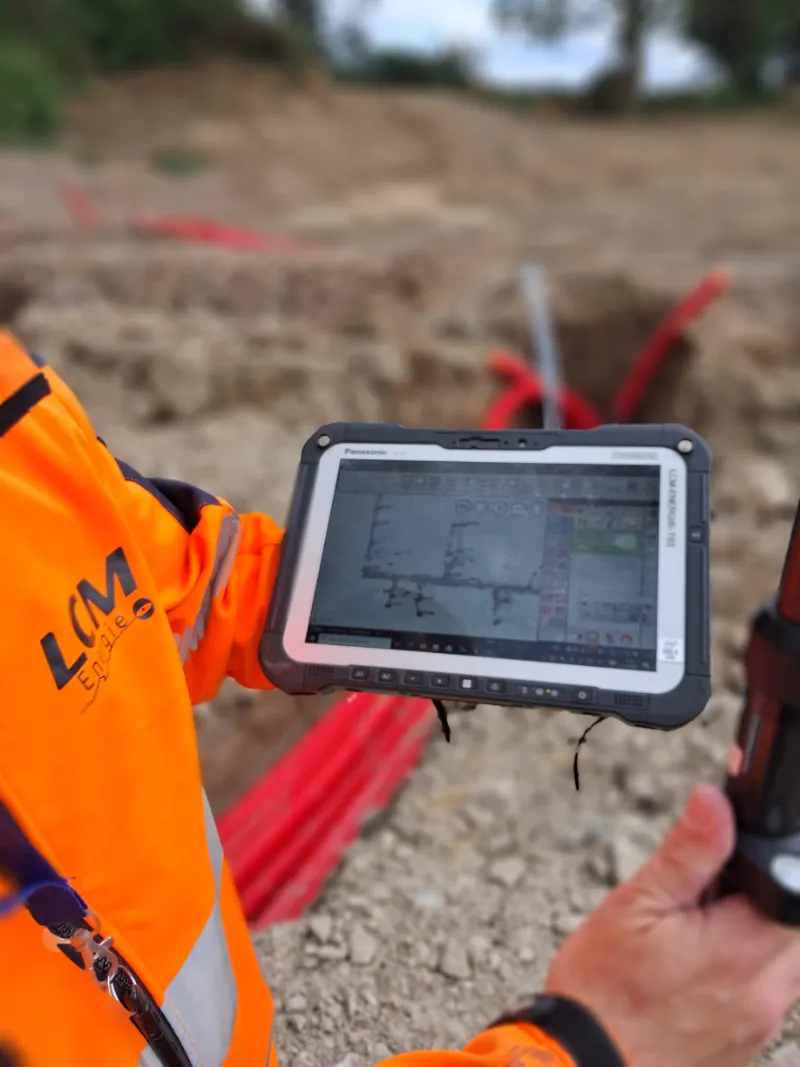 Opérateur en gilet haute visibilité utilisant tablette tactile robuste sur chantier de travaux publics