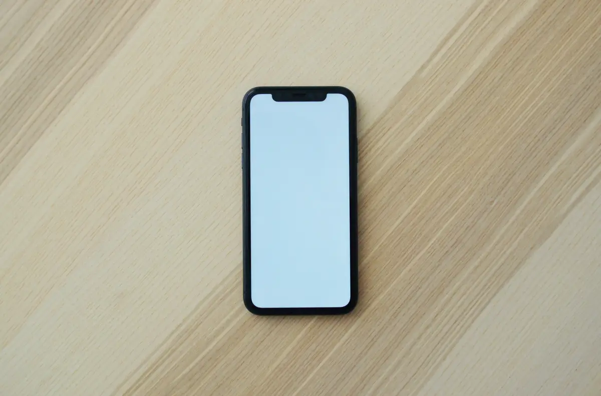 Uno smartphone con lo schermo vuoto su un tavolo di legno