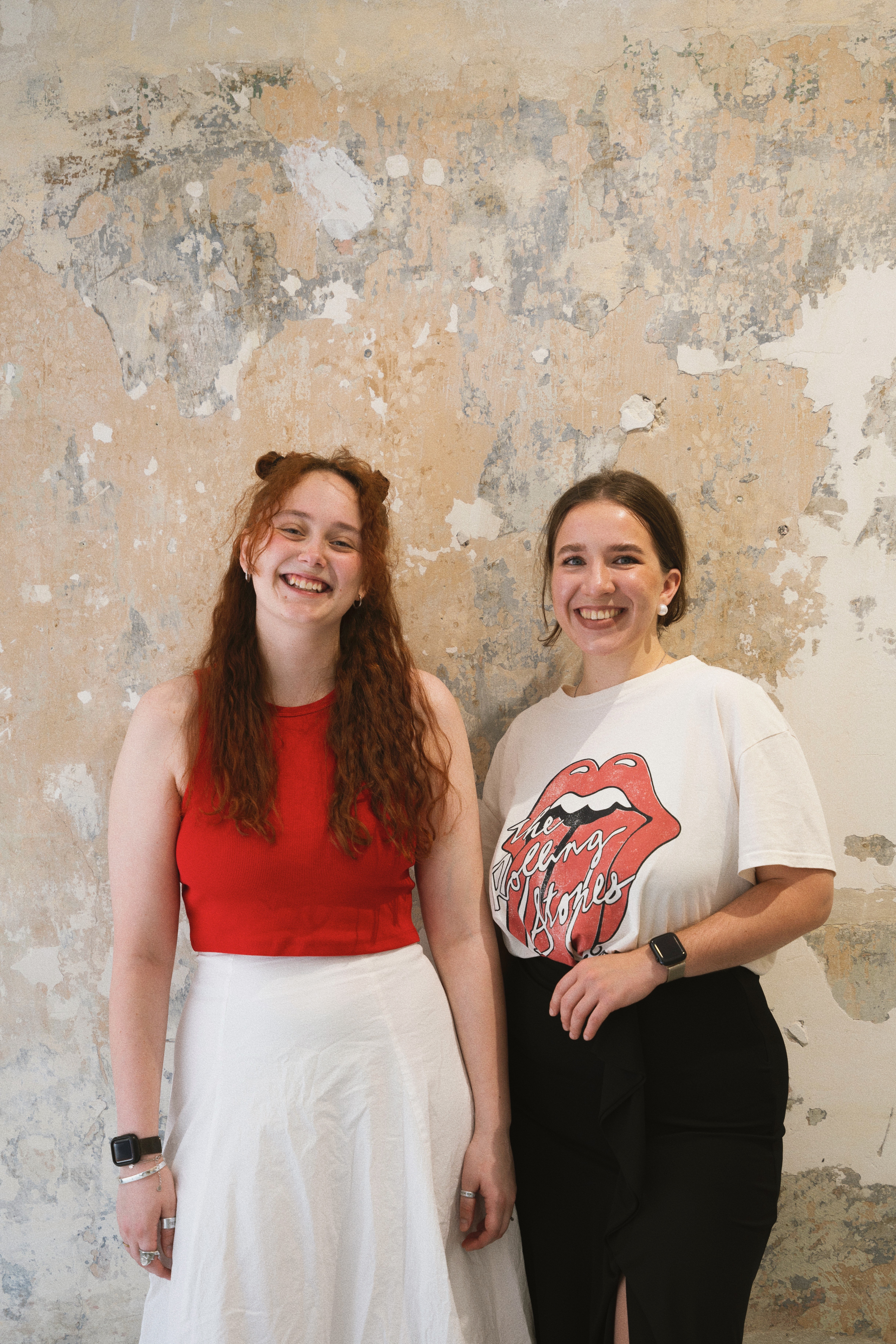Creative social media strategists behind a modern Vienna-based agency, smiling confidently in front of a textured studio wall — working with small businesses to build authentic online presence through content, Reels, and branding