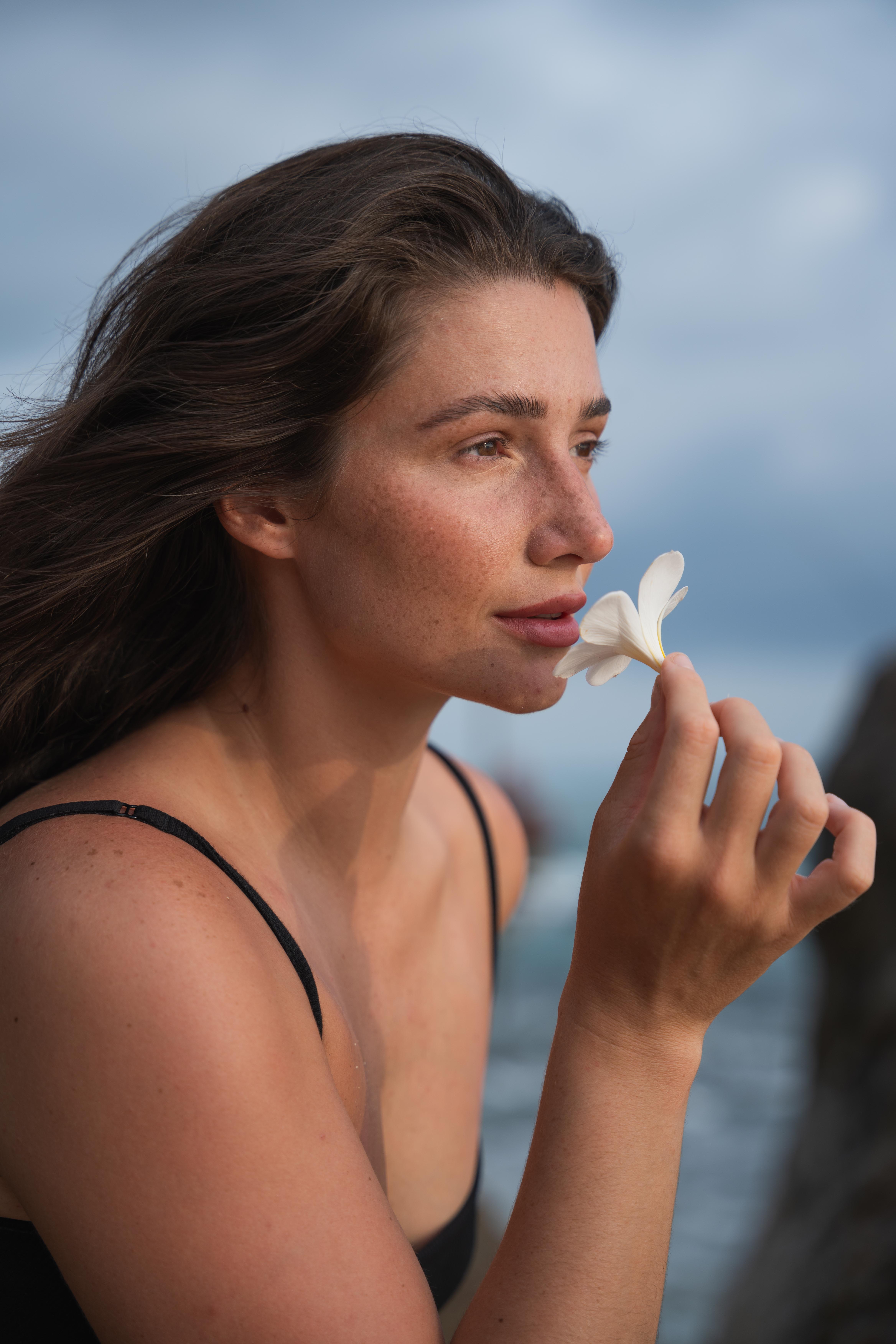 Girl smelling a white flower looking to the side