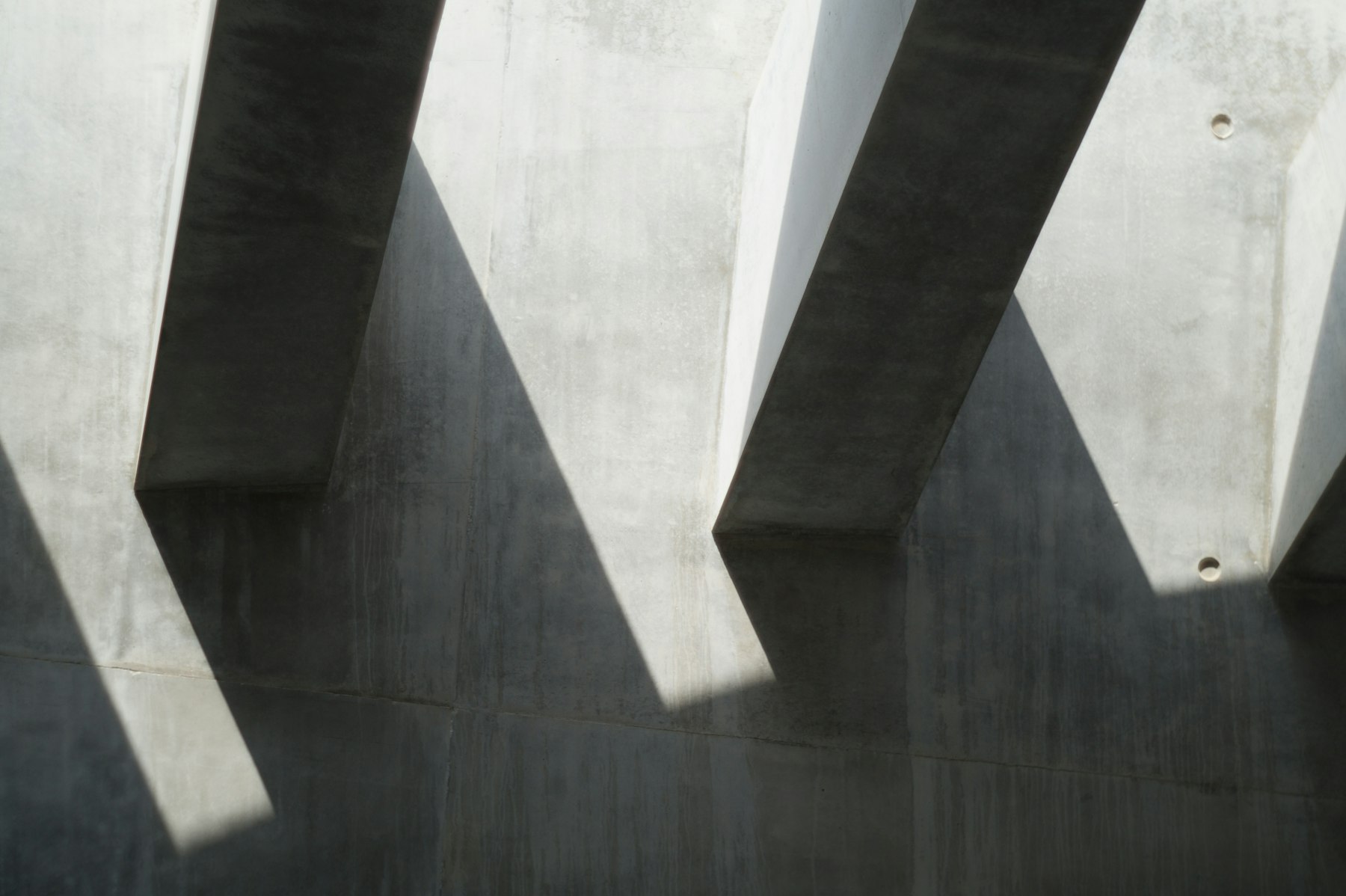 Concrete fins casting deep diagonal shadows on a wall
