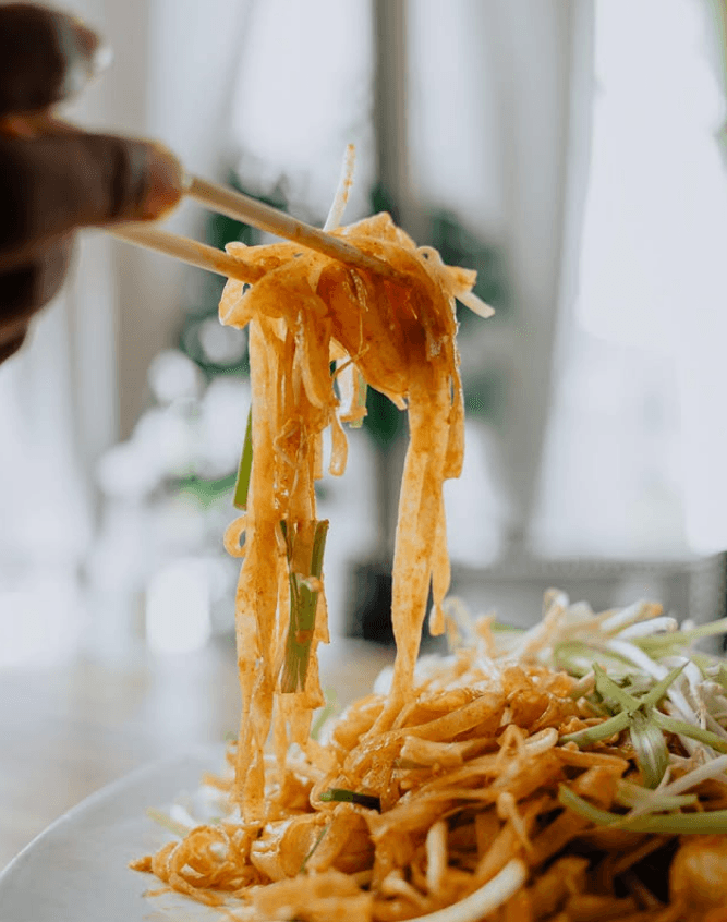 Chopsticks lifting the first bite of hand-pulled noodles