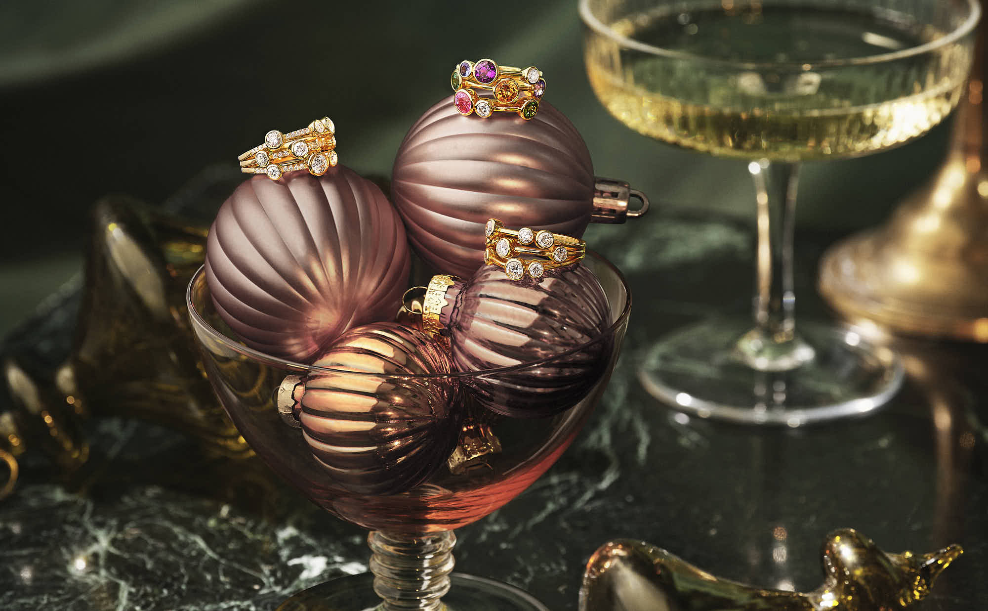 A close-up of three boodle rings sit on a stack of baubles, accompanied by a glass of yellow liquid.