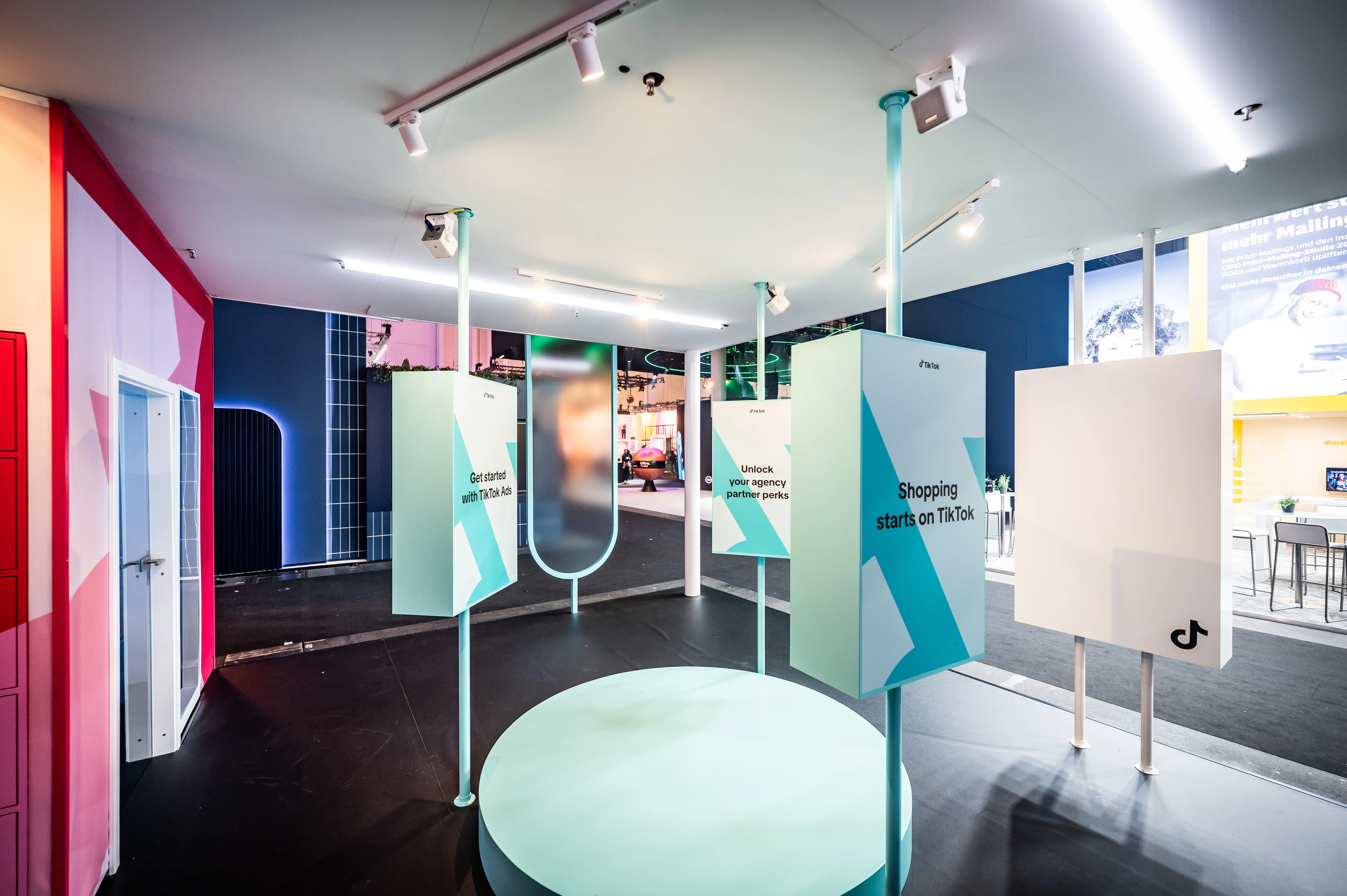 Mint-coloured info area with round podium and pillar displays about shopping on TikTok inside the booth.