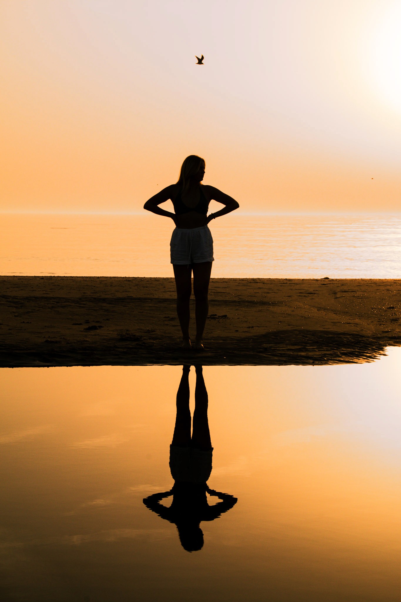 Sfeervolle foto van de reflectie op het natte zand van het strand tijdens zonsondergang, waarbij de kleuren en de rust van het moment worden vastgelegd