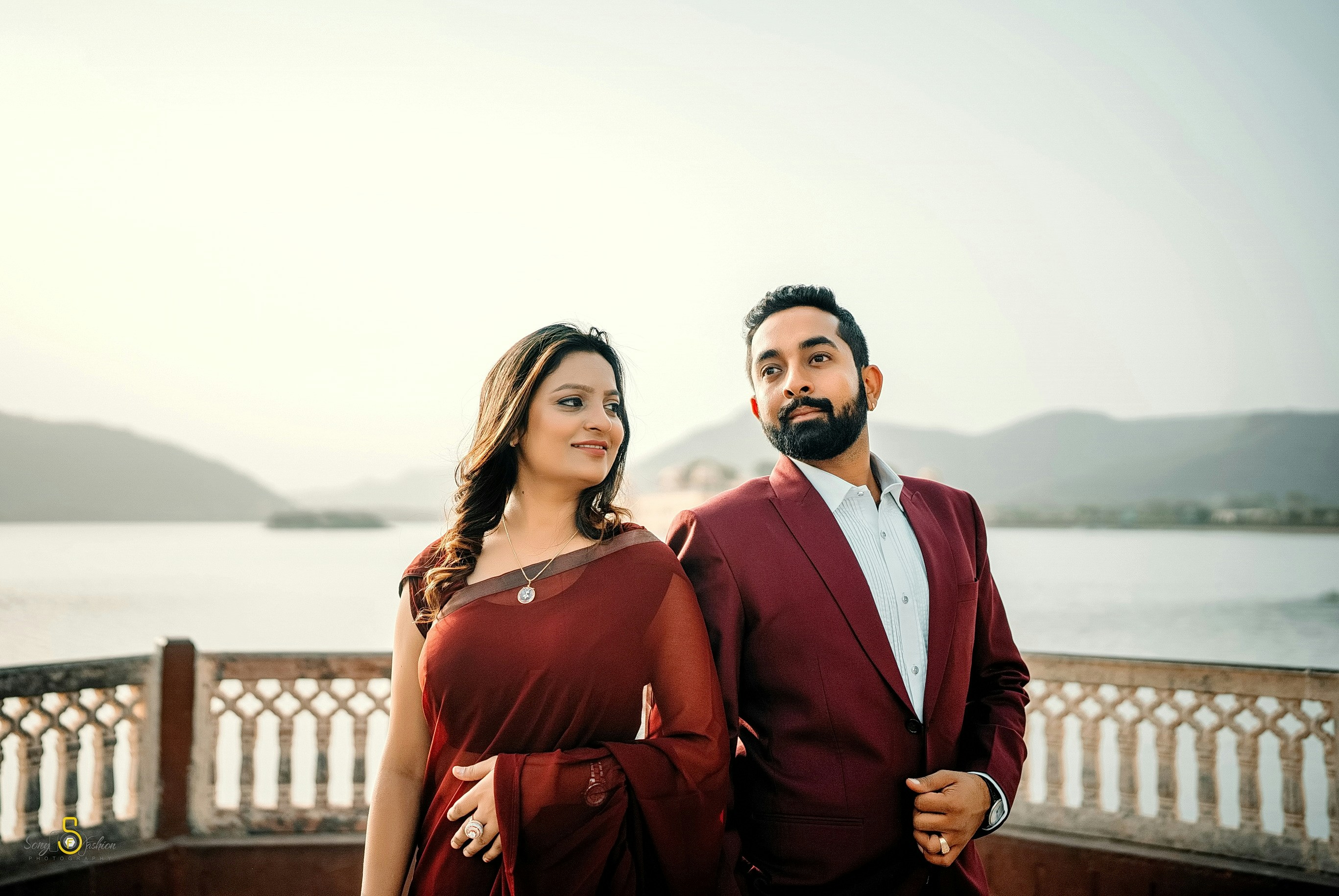 A couple poses by the water for a photo.