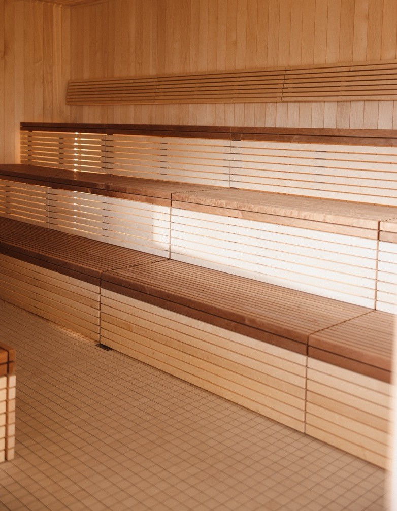 Warmly lit sauna room with wood benches