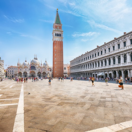 La Plaza de San Marcos de Venecia, con el campanario y la Basílica de San Marcos al fondo, rodeada de edificios históricos y turistas.