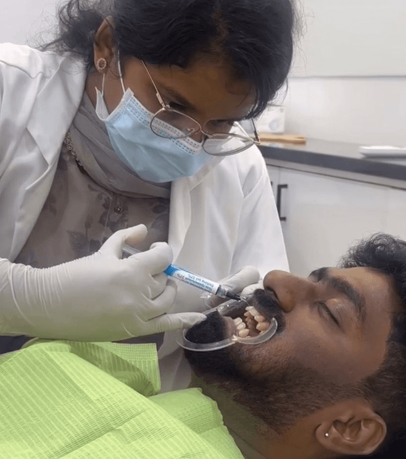 Dental professional placing clear aligner in patient’s mouth with digital teeth image on monitor